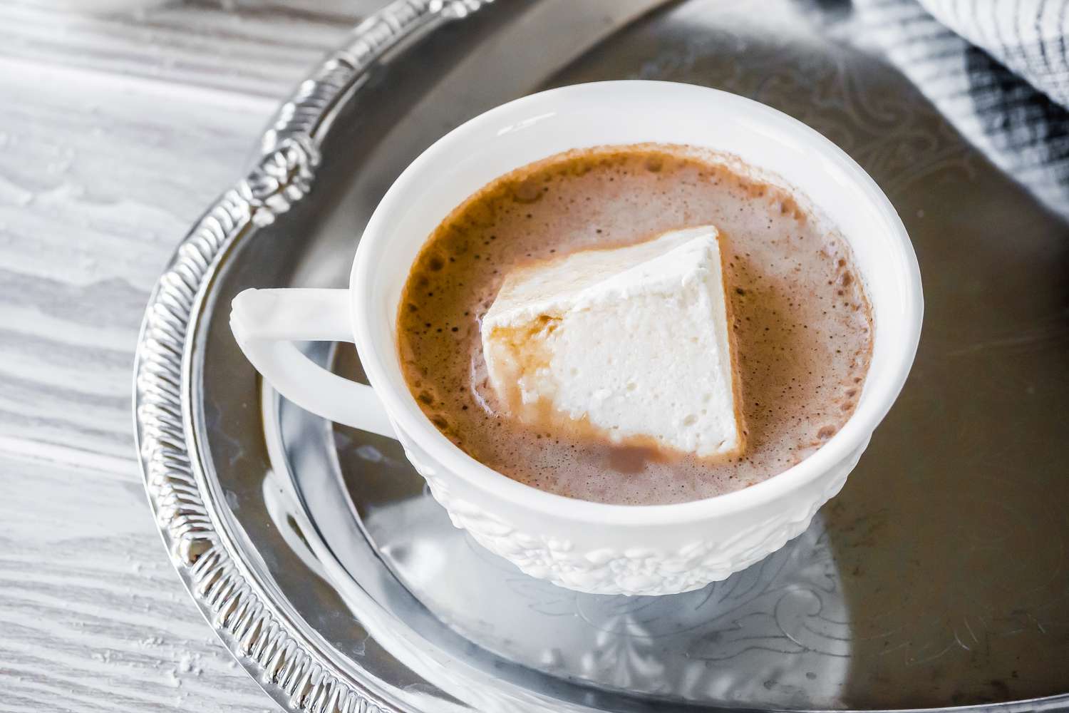 Cup of Hot Cocoa with a Large Vegan Marshmallow on a Tray Next to a Kitchen Towel