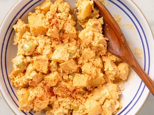 overhead view of Deviled Egg Potato Salad in a bowl with a wooden spoon