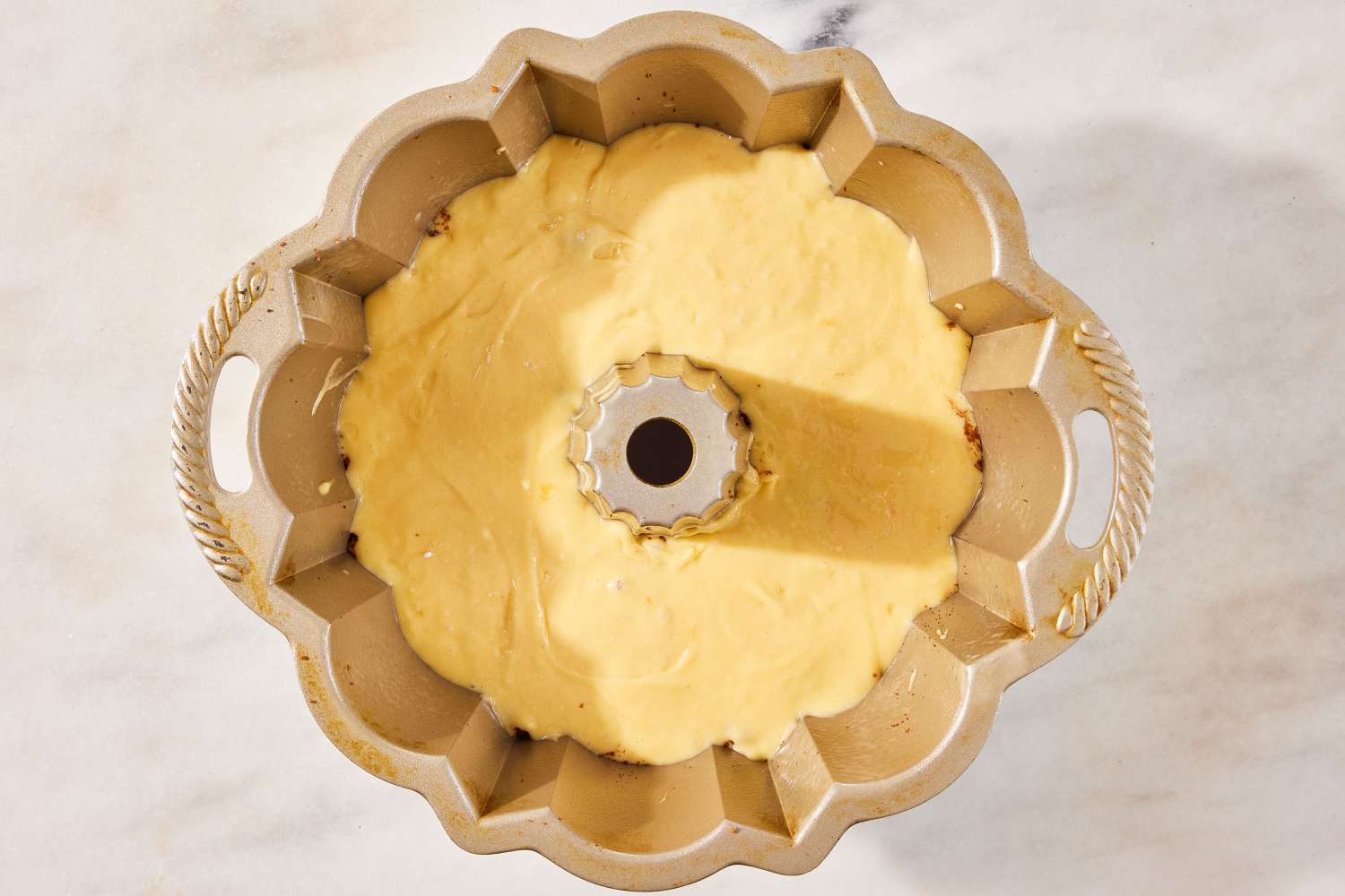 yellow cake batter poured on top of previous nut layer in bundt pan for Sock It to Me Cake