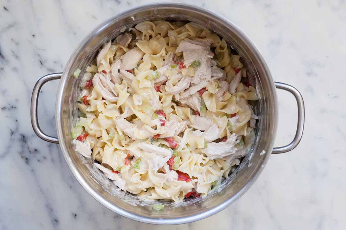 Chicken, noodles and sauce in silver pot.