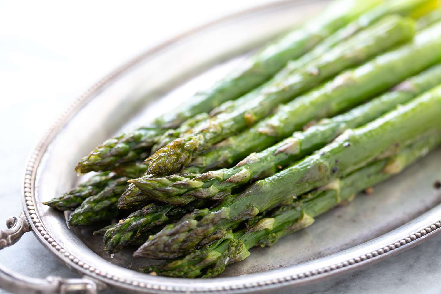 A pile of Roasted Asparagus on silver platter
