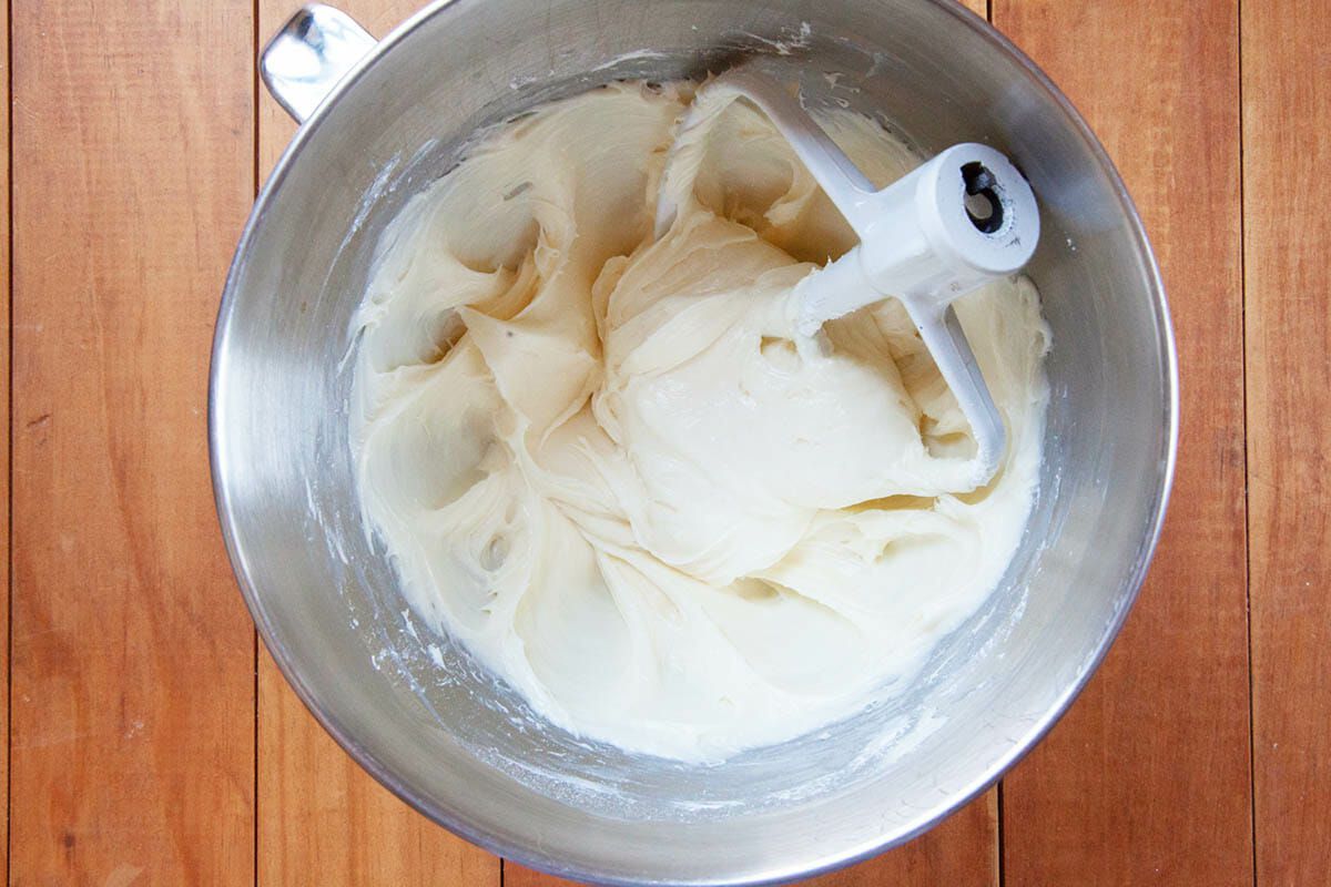 A metal bowl with a paddle attachment set in the cream cheese frosting to make Easy Gingerbread Bars.