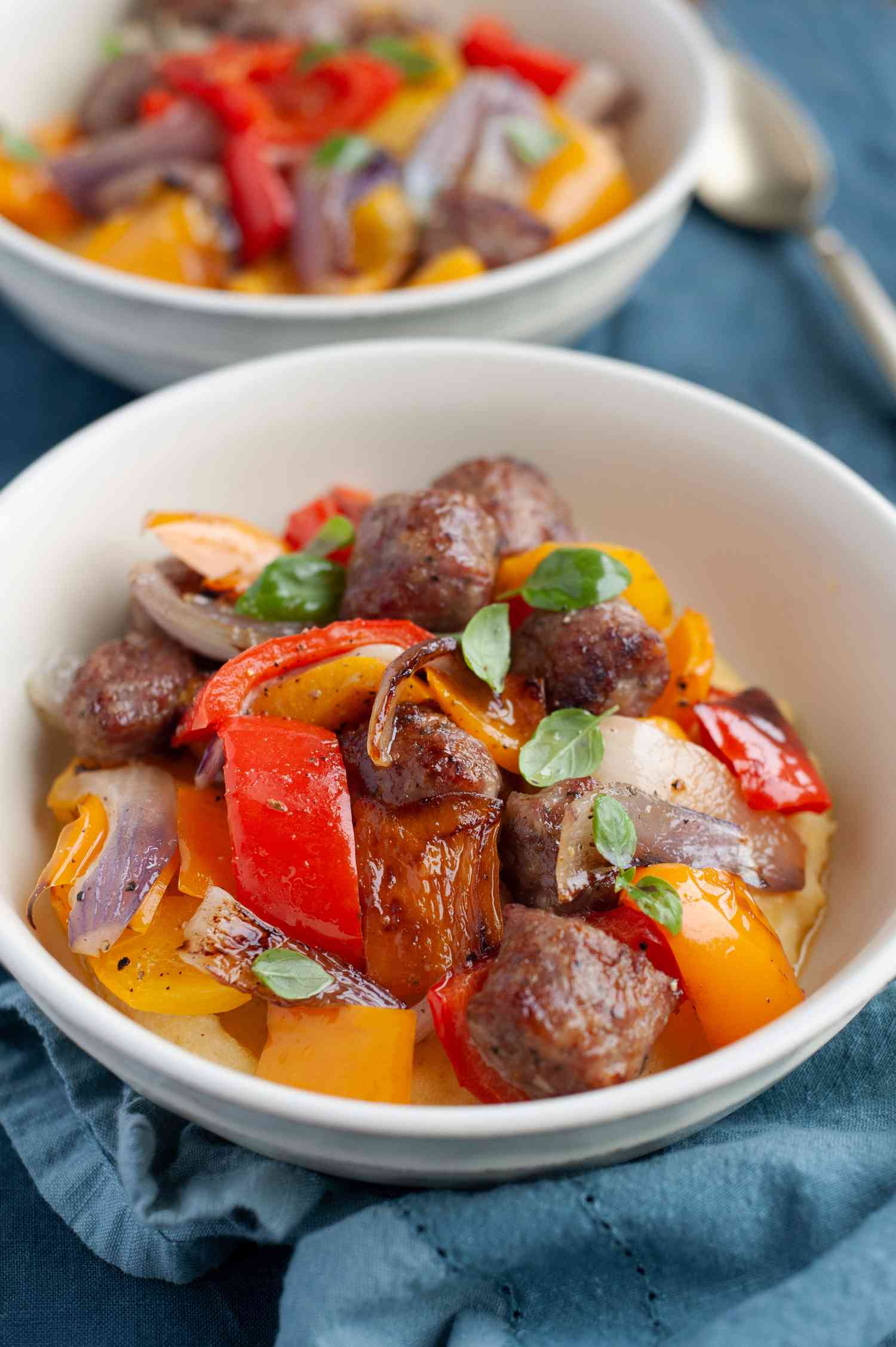 Two bowls of sheet pan Italian sausage, peppers, and onions