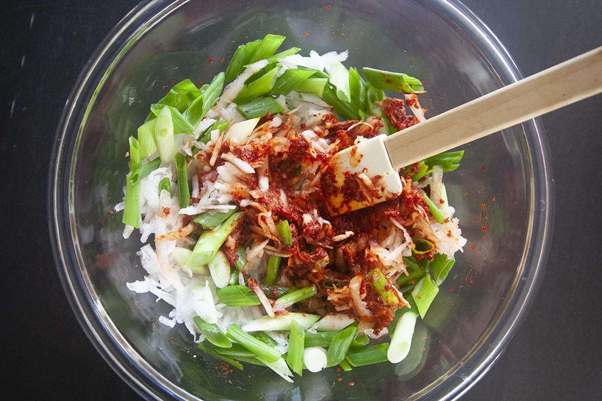 A flexible spatula mixes ingredients to show how to make kimchi.