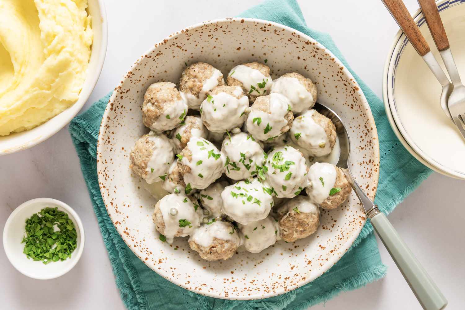 A plate of Konigsberger Klopse meatballs served with creamy sauce and a side of mashed potatoes