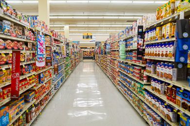 View looking down a grocery store aisle with canned tomatoes, pasta and sauce, rice and beans, soups and asian items on the shelves