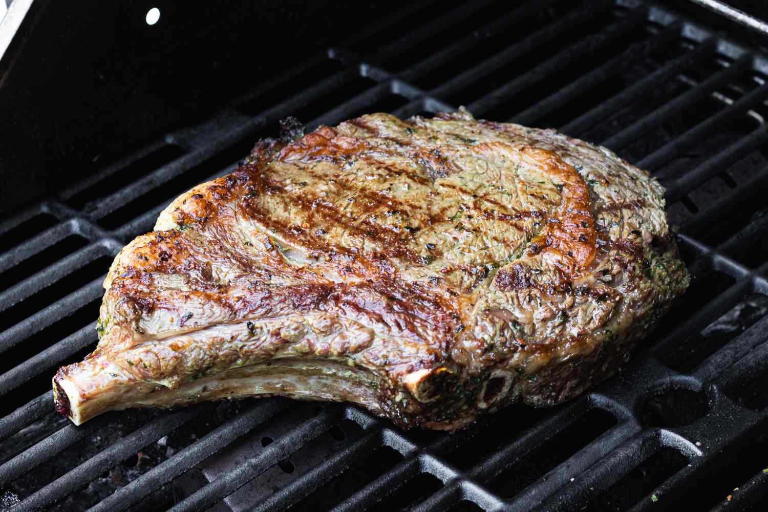 A cowboy steak cooking on the grill.