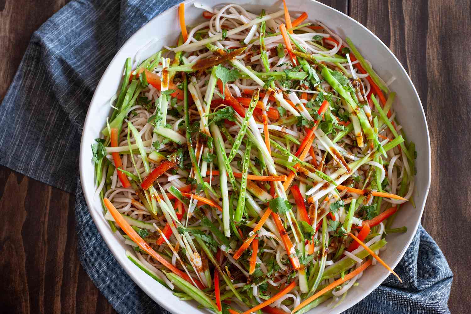 Vegetable rice noodle salad in a serving bowl with a linen underneath.