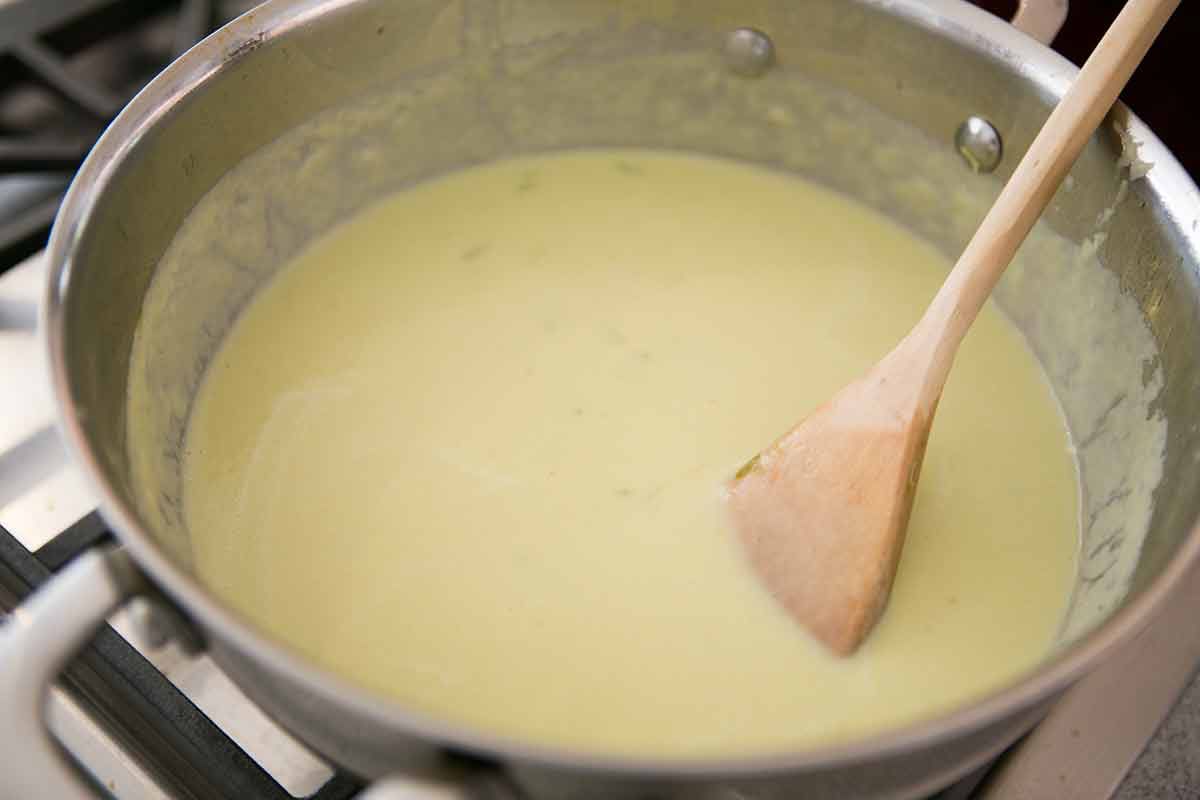 Creamy celery soup in a soup pot being stirred with a wooden spoon