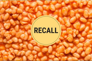 A zoomed in photo of baked beans with a recall sticker in the center. 
