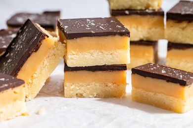 Closeup view of a stack of Millionaire Shortbread bars on parchment paper with several bars visible in the background