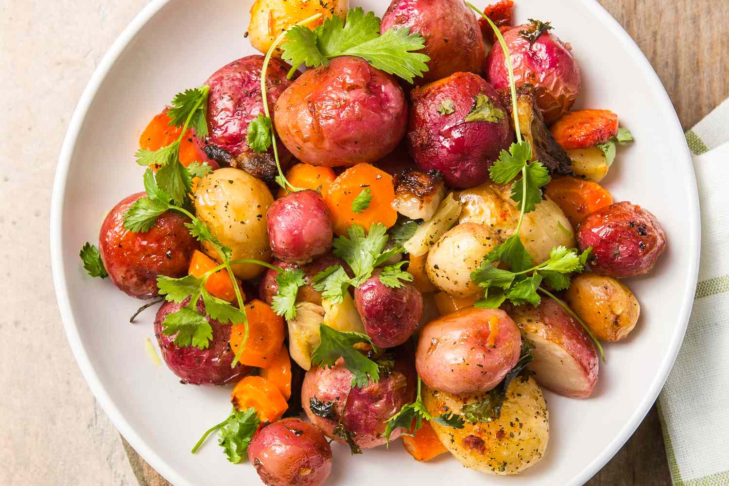 A plate of roasted root vegetables with garnish including potatoes and carrots