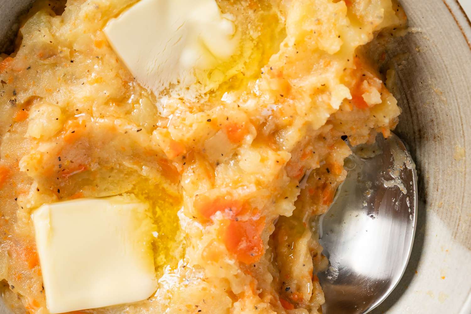 Mashed vegetable dish with melted butter and a spoon