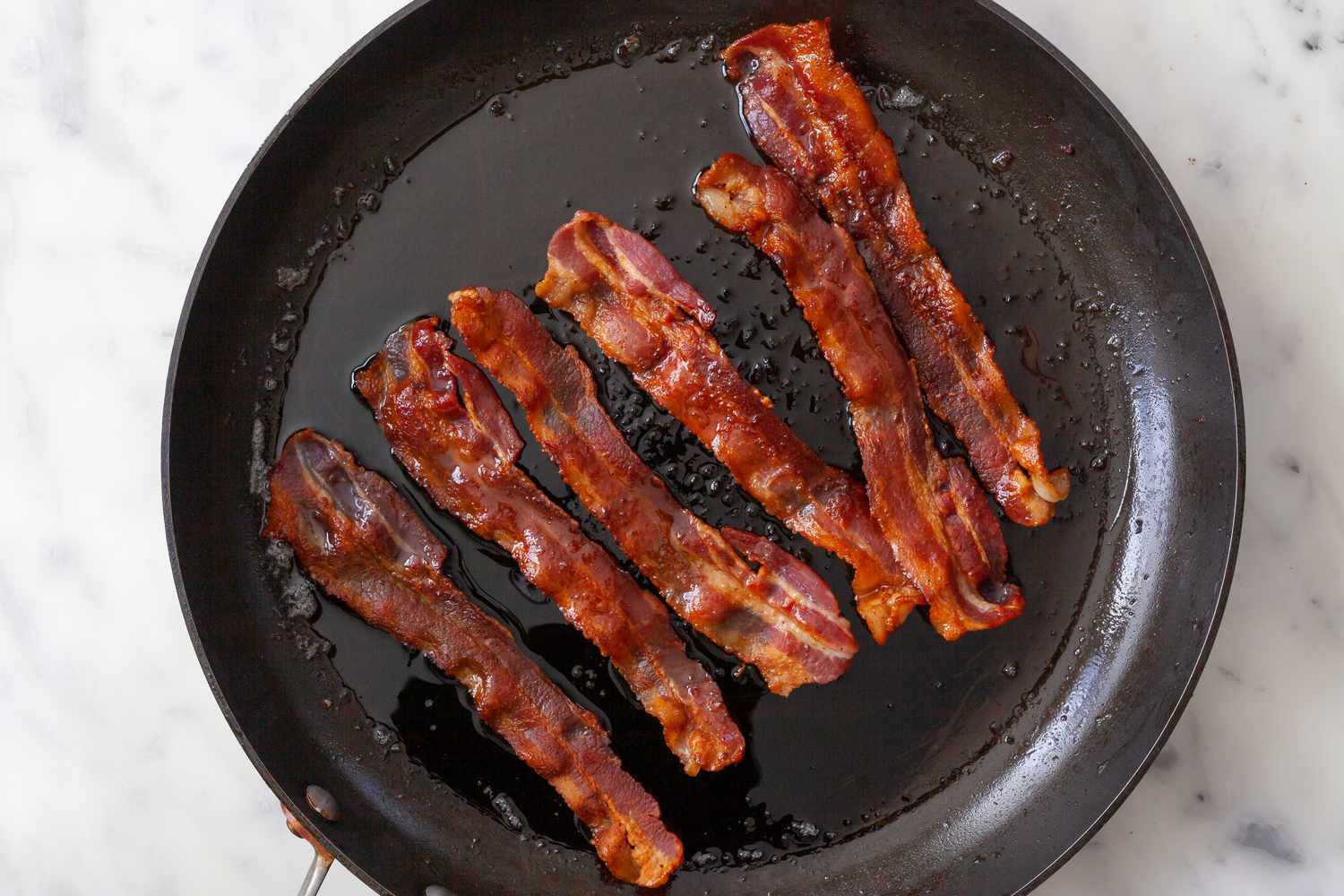 Crisping bacon in a skillet to make a cobb salad.