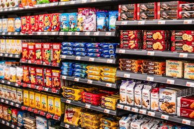 Grocery store shelves stocked with various packaged snacks including cookies crackers and chips