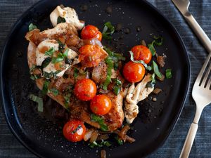 Chicken caprese on a black plate. 