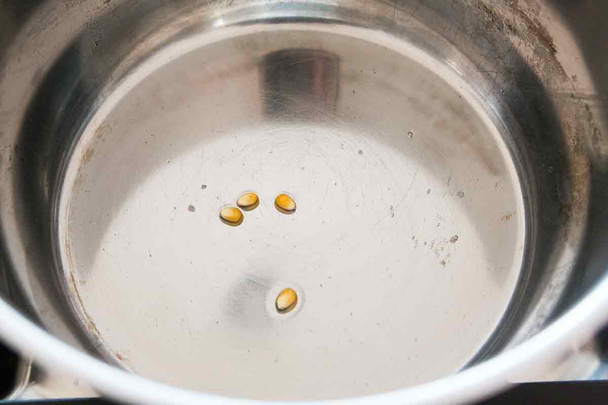 heat oil and add 3 to 4 popcorn kernels to the pot