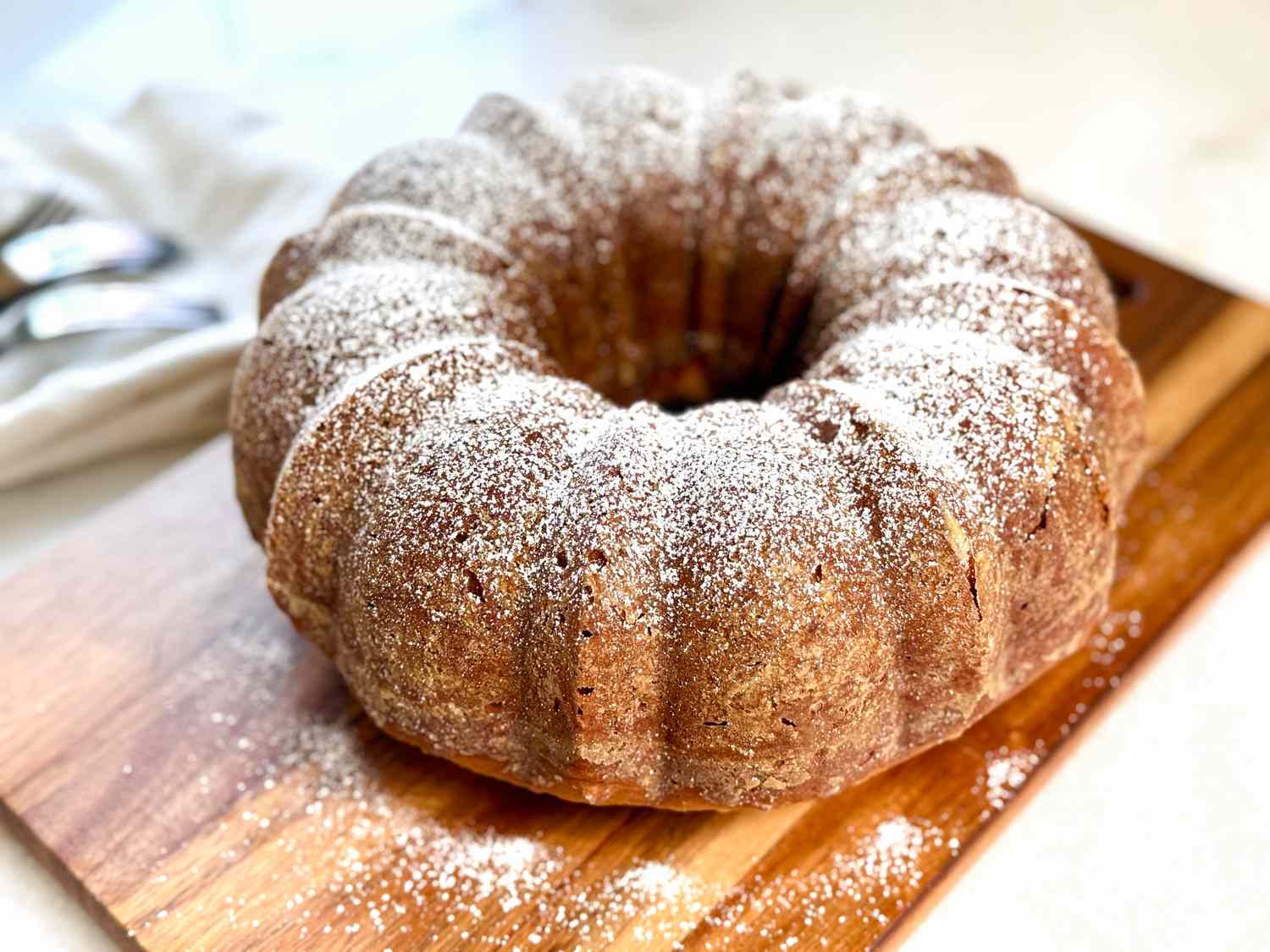 Bundt cake dusted with powdered sugar on a wooden board