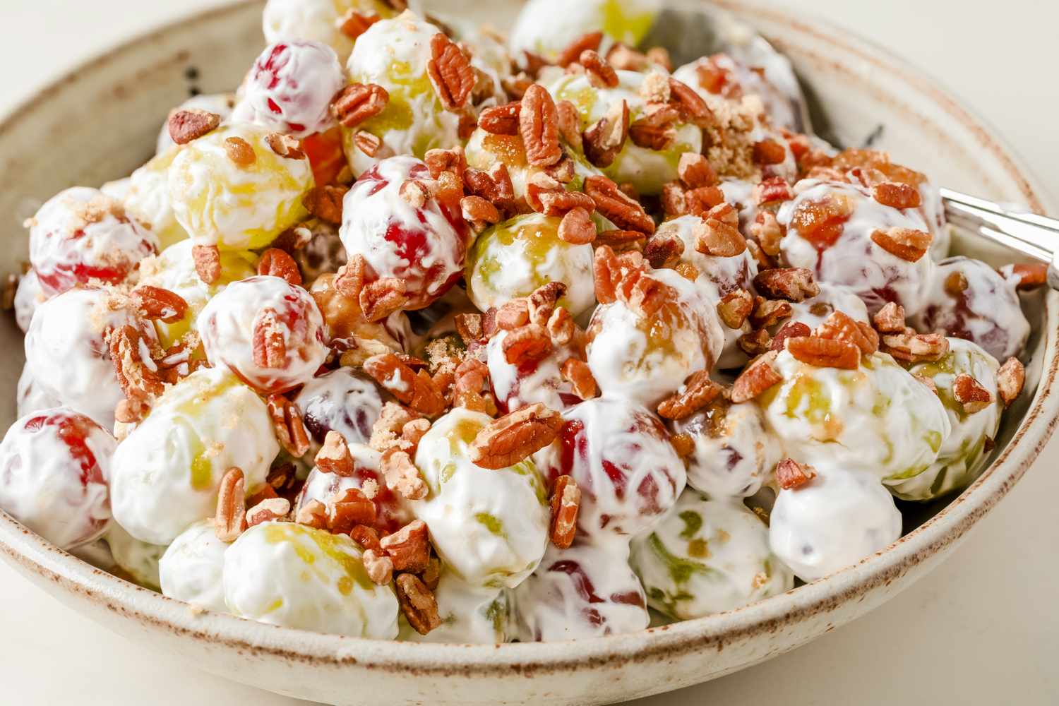 Bowl of grape salad topped with chopped nuts