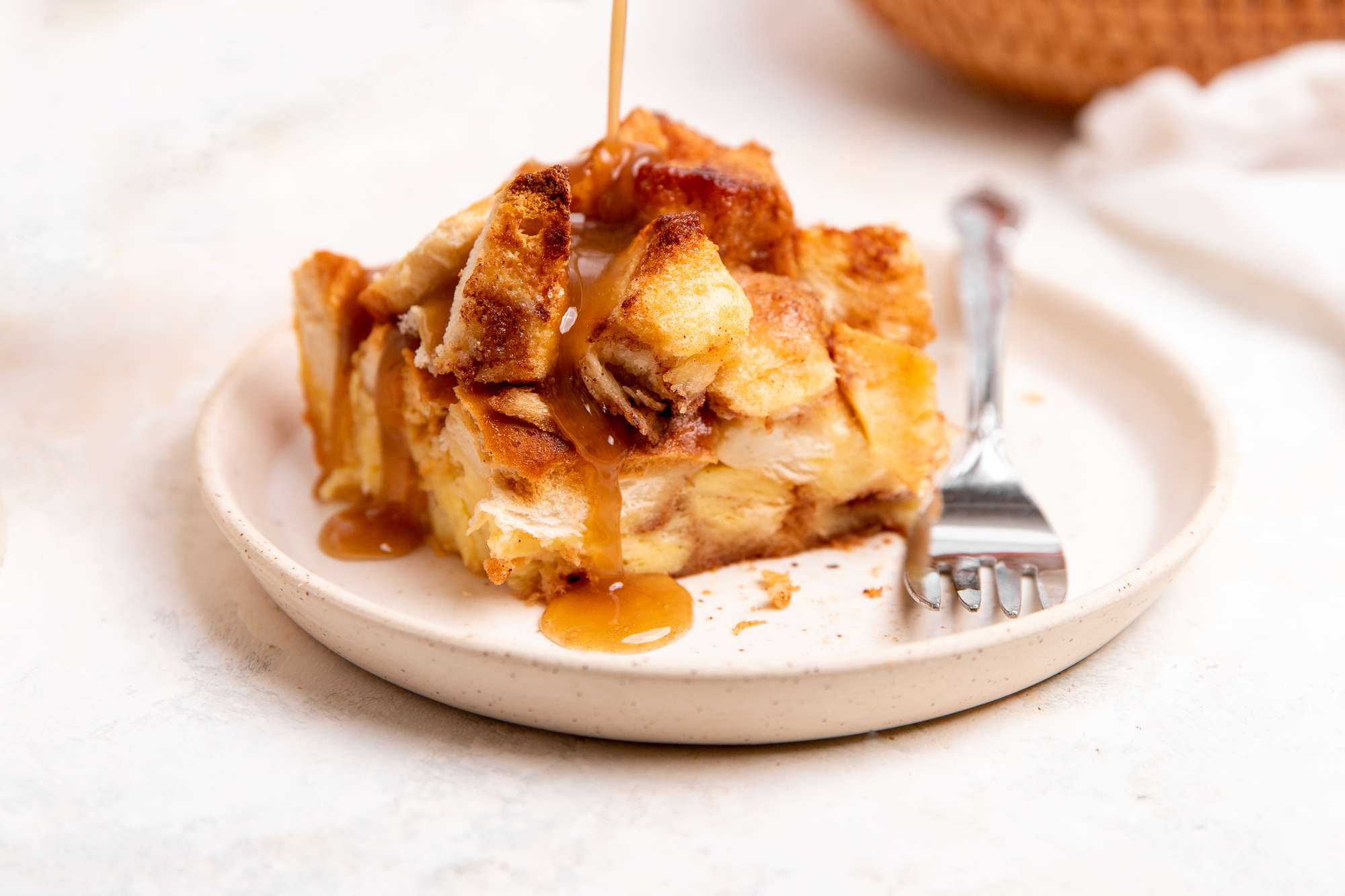Slice of Apple Bread Pudding on a Plate with Sauce Drizzling