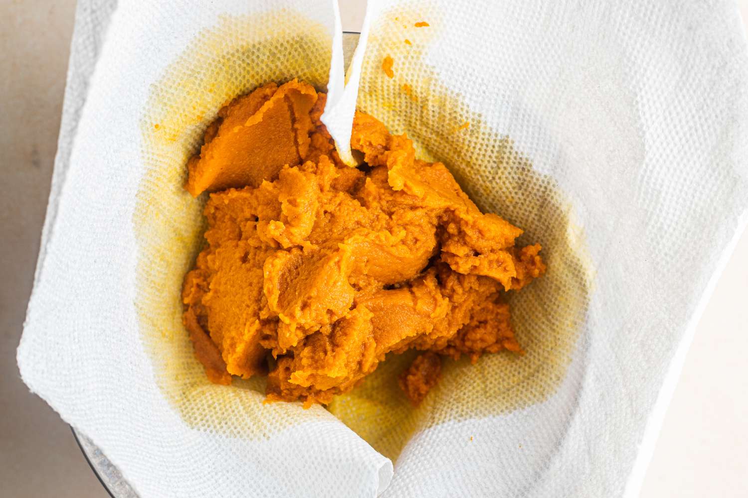 Pumpkin Puree Drained in Layer of Paper Towels Over a Colander for Pumpkin Ladoo Recipe