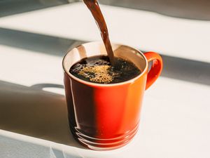 Coffee being poured into an orange mug