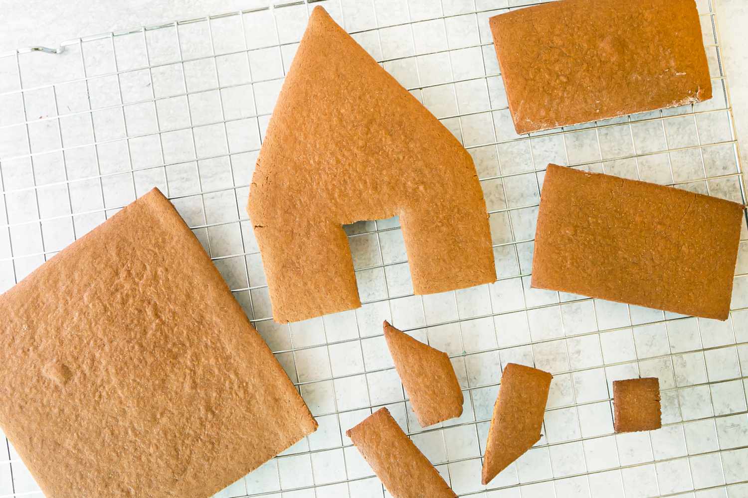 The pieces of a gingerbread house cooling on a rack.