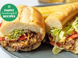 Two sandwiches filled with ground meat, lettuce, and tomato on a plate, with a Simply Weeknight Recipes logo