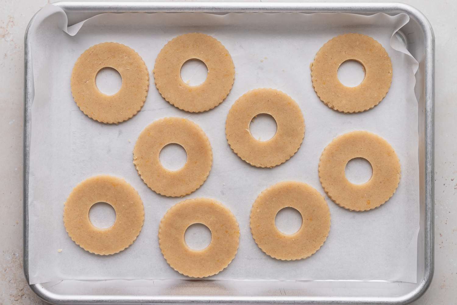 Donut shaped cookies on a baking sheet to make classic linzer cookies.