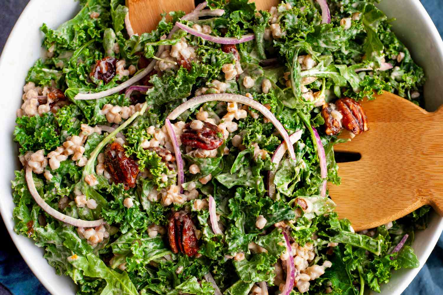Bowl of Kale and Farro Salad with Spiced Candied Pecans with a Pair of Salad Servers