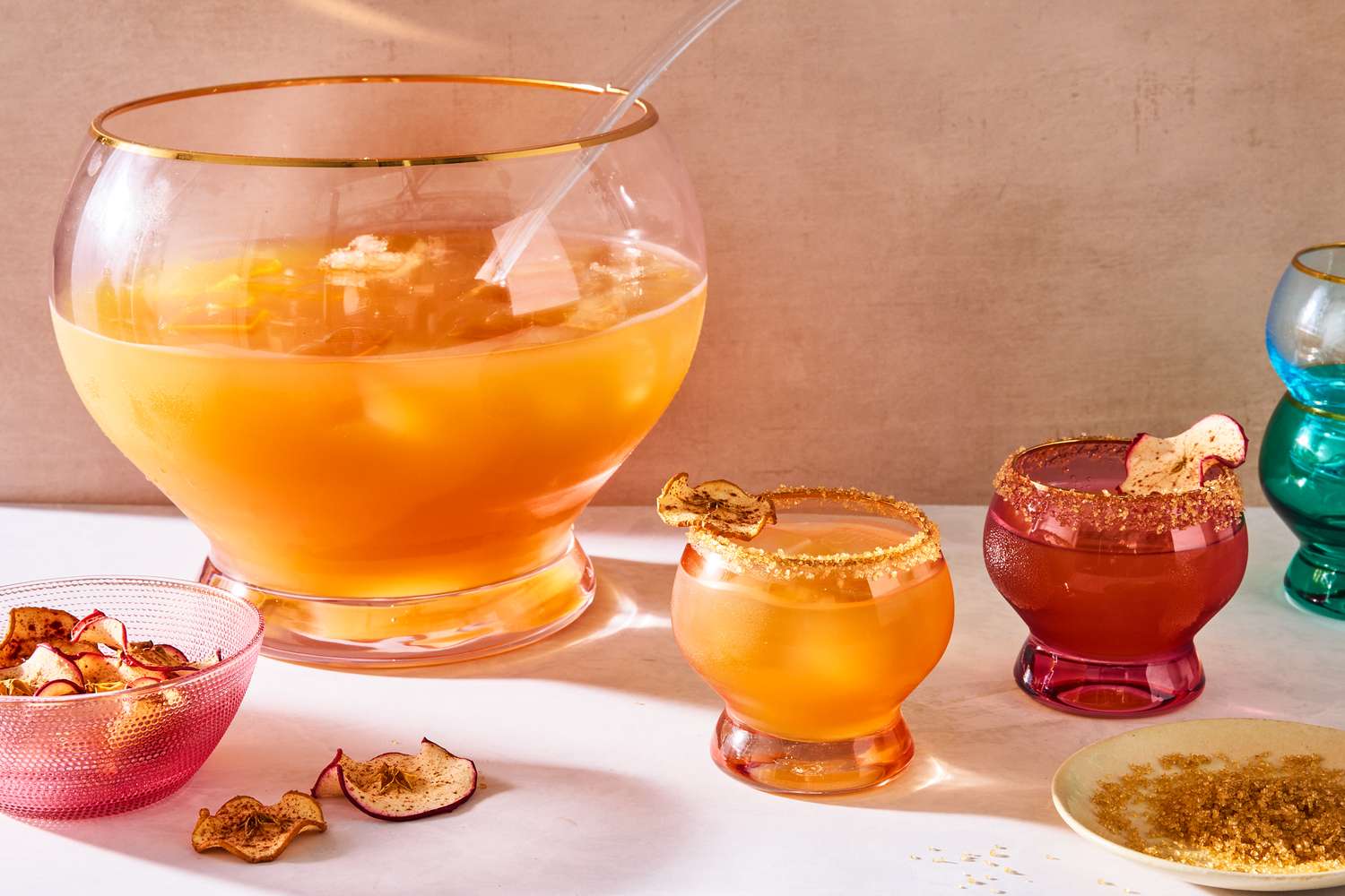 A punch bowl with whiskey cider punch and several garnished glasses on a table