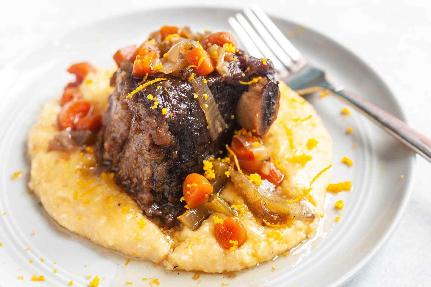 Beef Short ribs braised in the slow cooker and served with polenta on a round plate