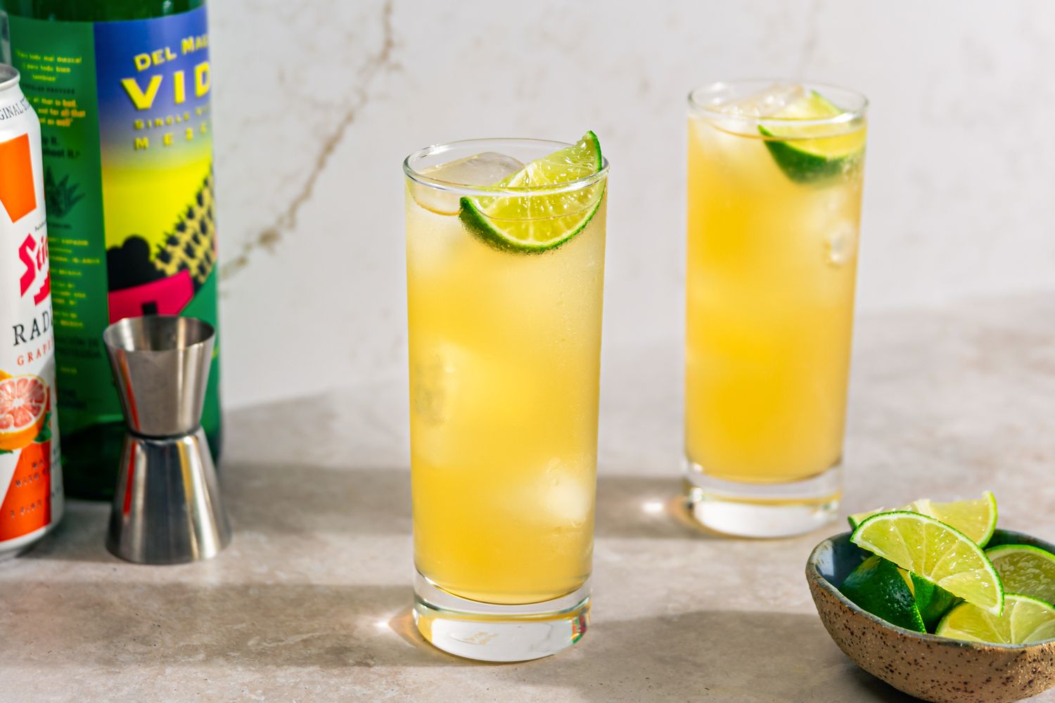 2 glasses of Mezcal Shandy cocktails garnished with lime slices