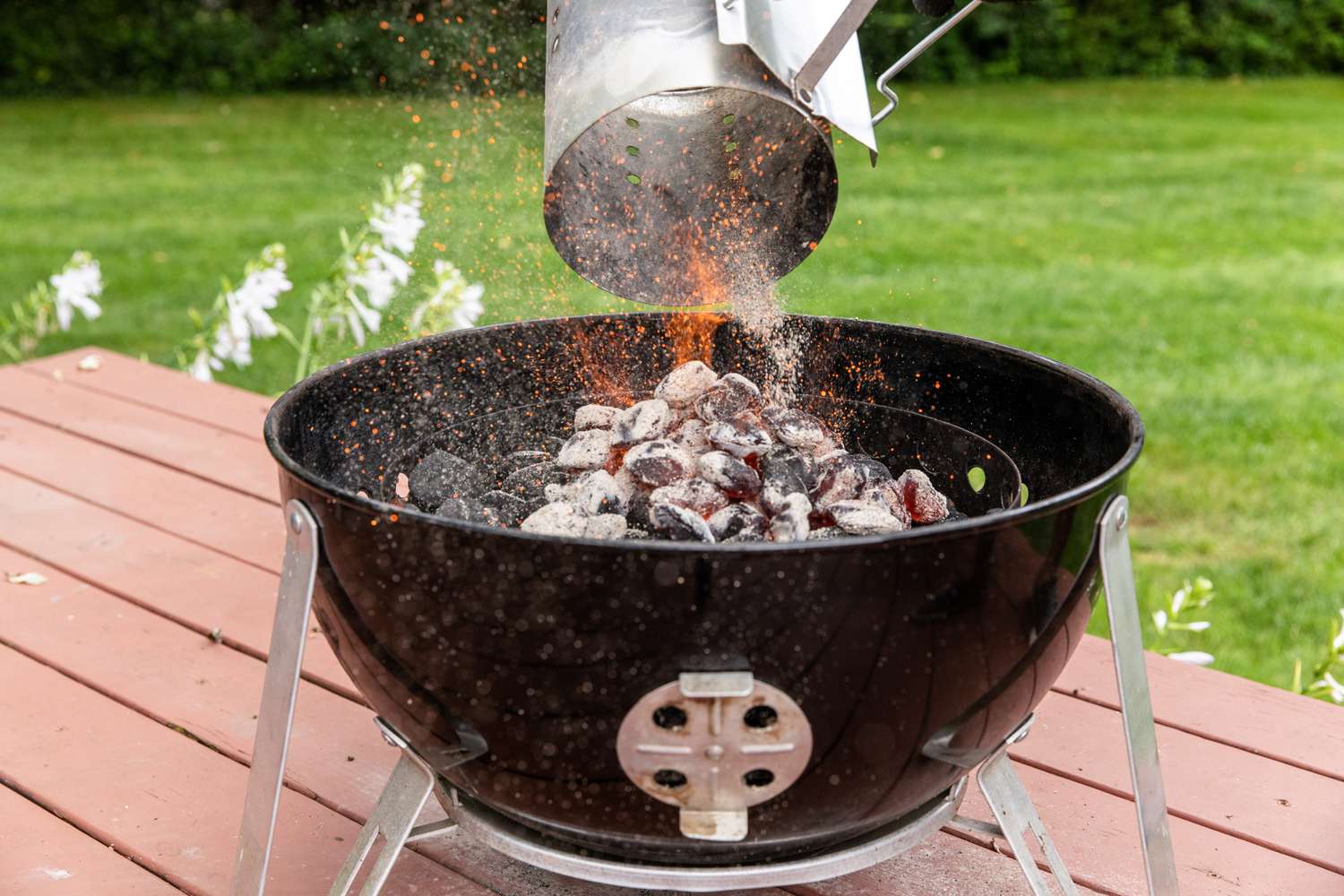 Adding hot coals to a grill to make a pecan wood smoked turkey