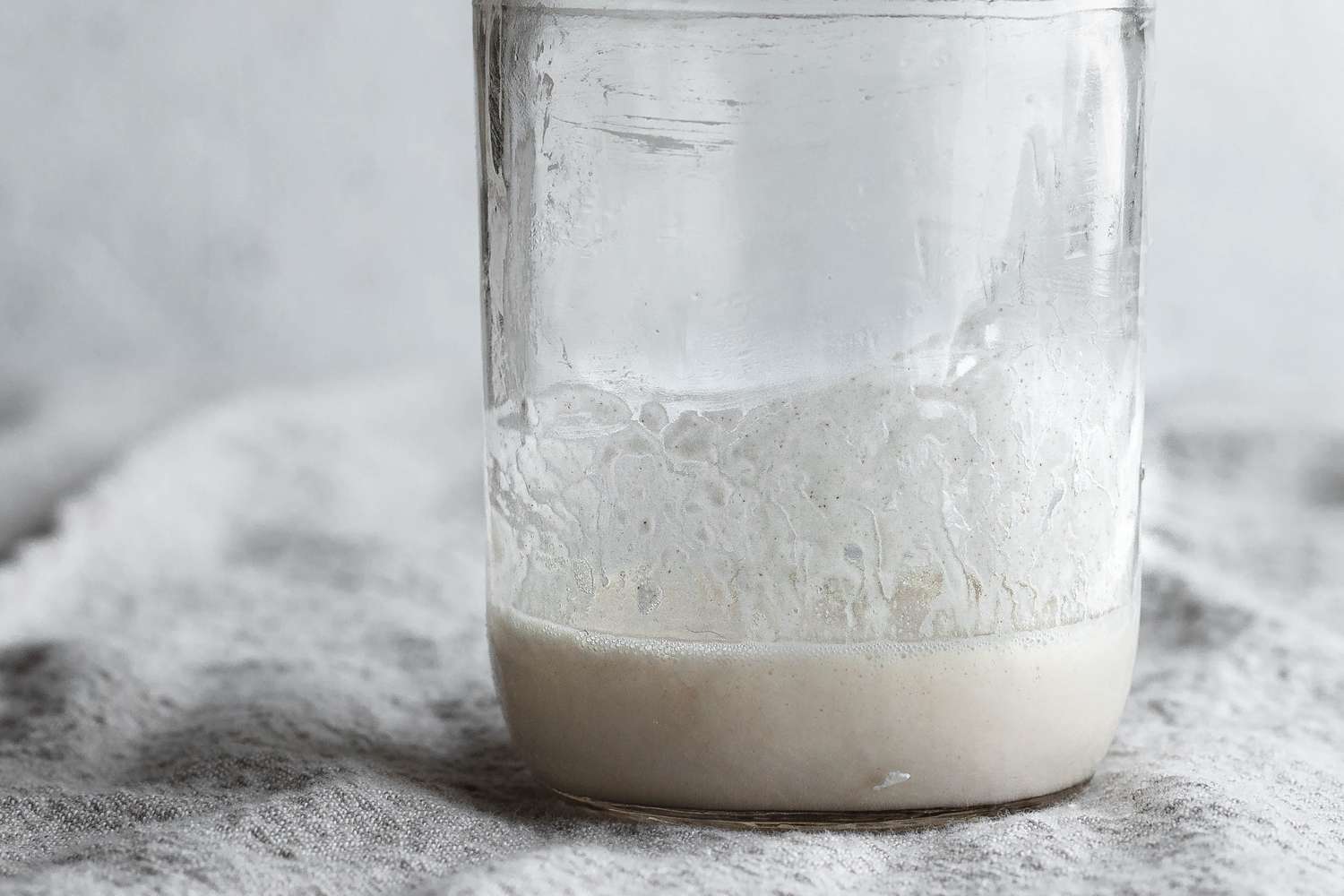 Close up of a mason jar with a homemade sourdough starter bubbling.