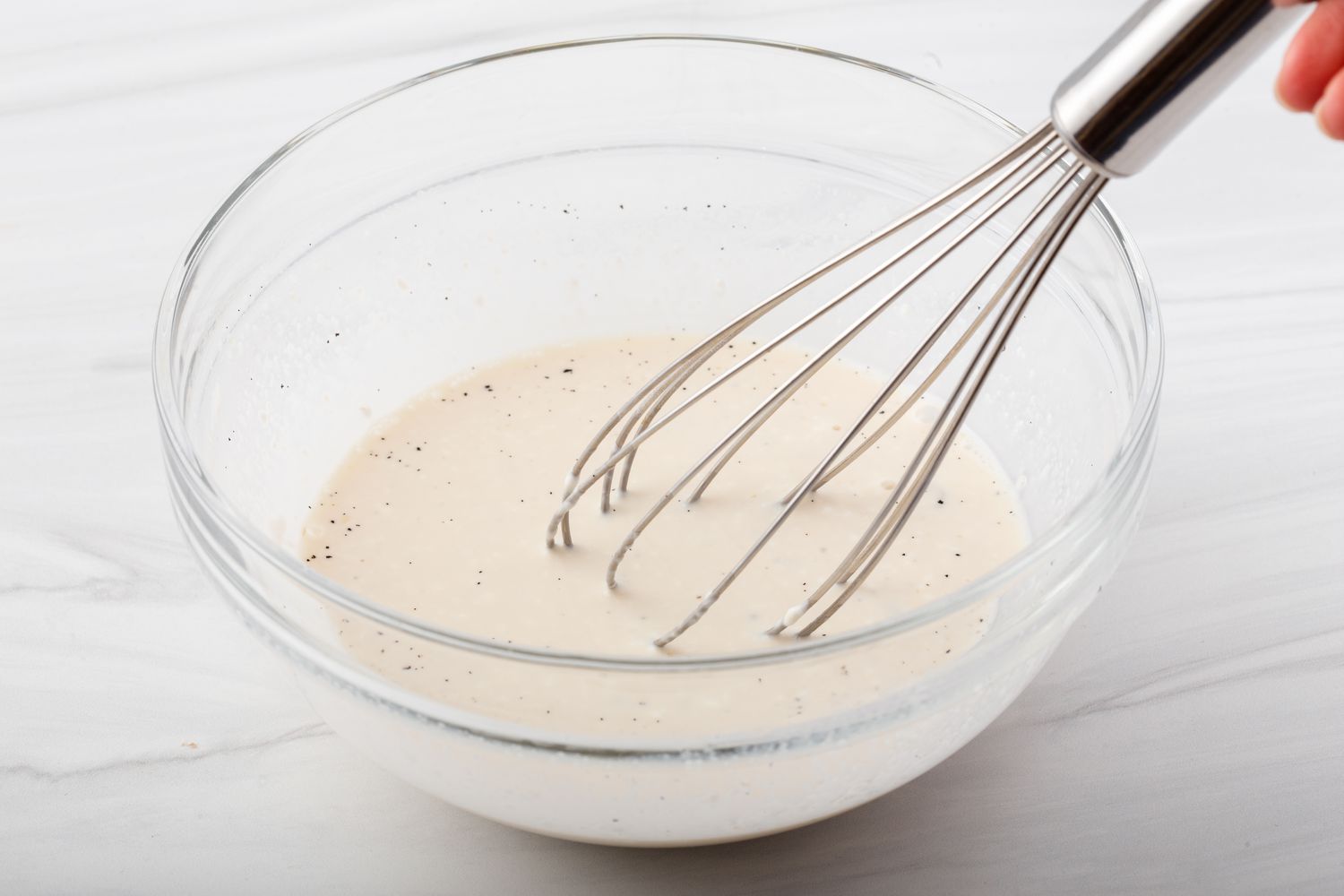 Whisking cream in a glass bowl to make the best vanilla cupcake recipe.