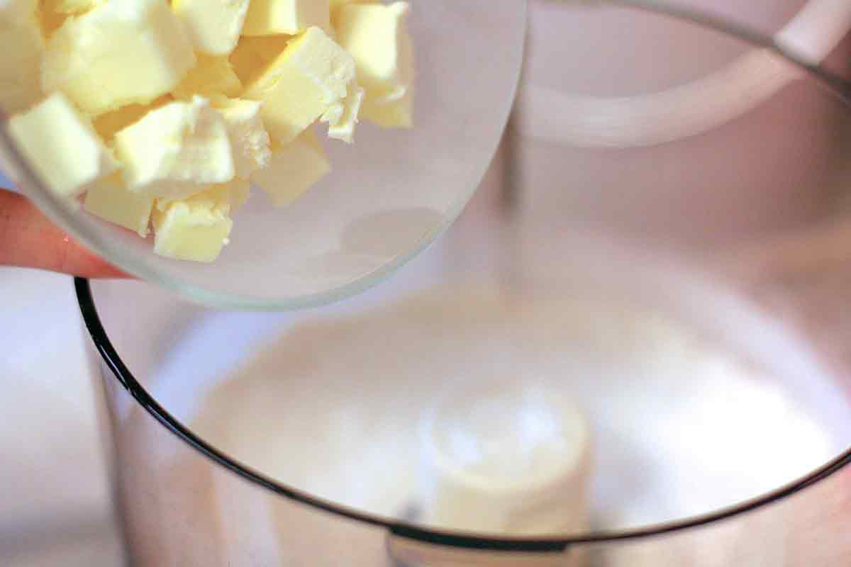 Cubed butter dumped into the bowl of a food processor to make the crust for a pot pie.
