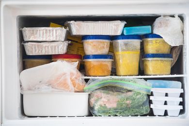 A freezer stocked with various containers and bags of frozen food