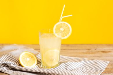 A glass of lemonade with lemon slices and straws on a striped cloth