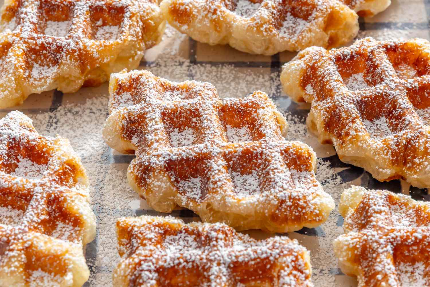 Croffles dusted with powdered sugar arranged on a grid surface