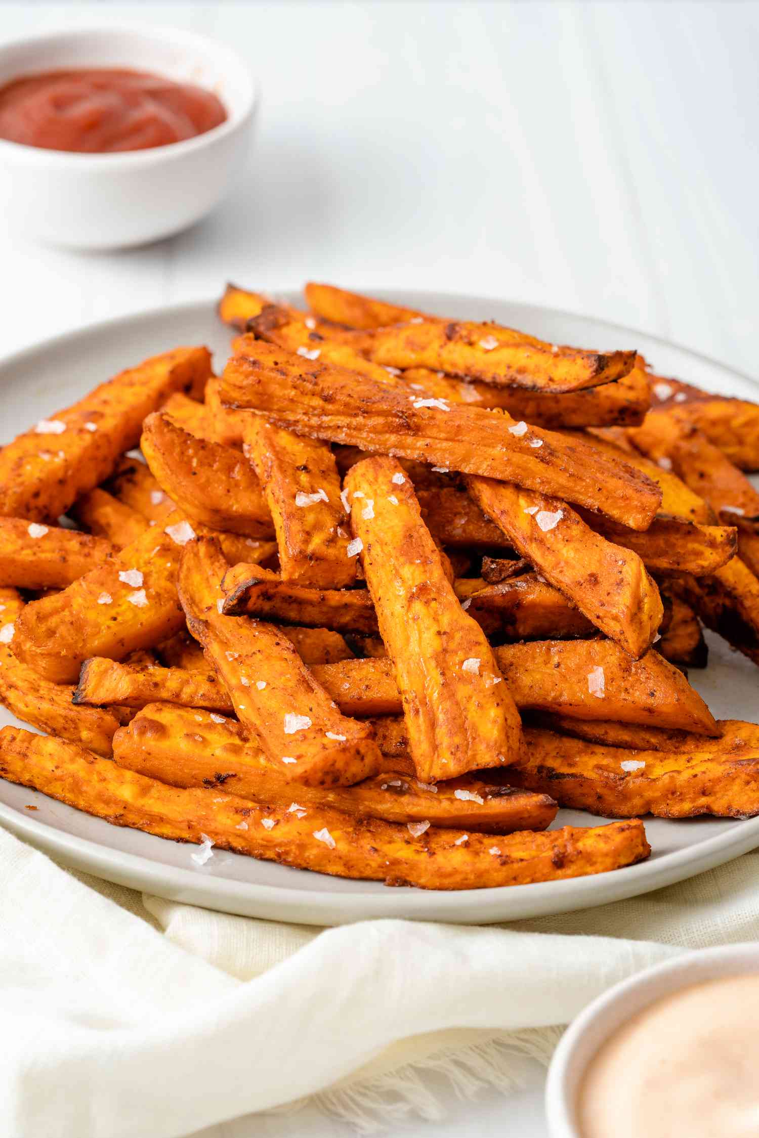 Side view of a platter of homemade sweet potato fries with salt sprinkled on top 