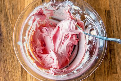 A glass bowl of strawberry butter with a spoon in it