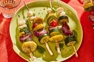 Vegetable skewers with zucchini, yellow squash, tomatoes, and mozzarella on a green plate