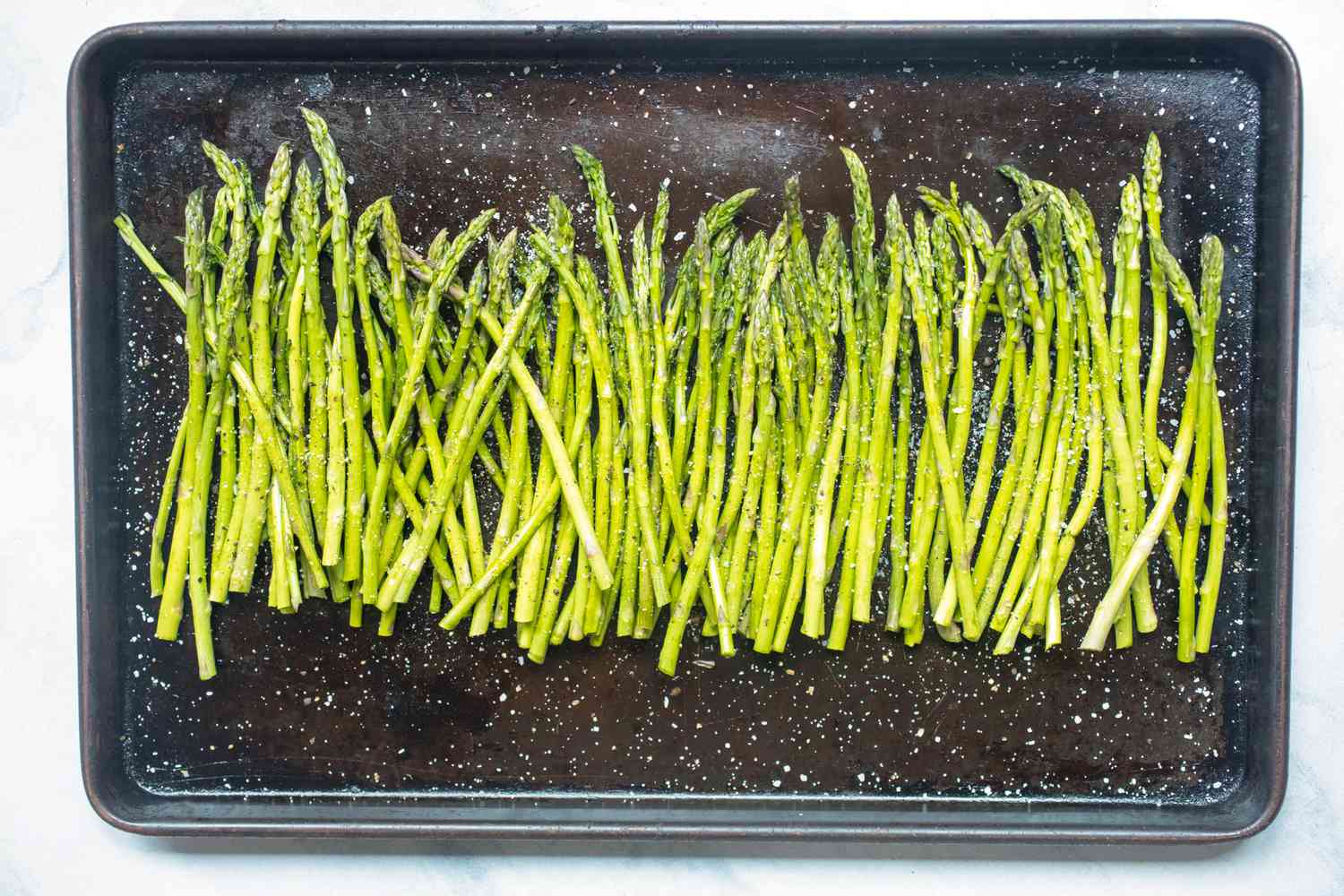 Baking sheet with asparagus on it to make one pan garlic shrimp and asparagus.