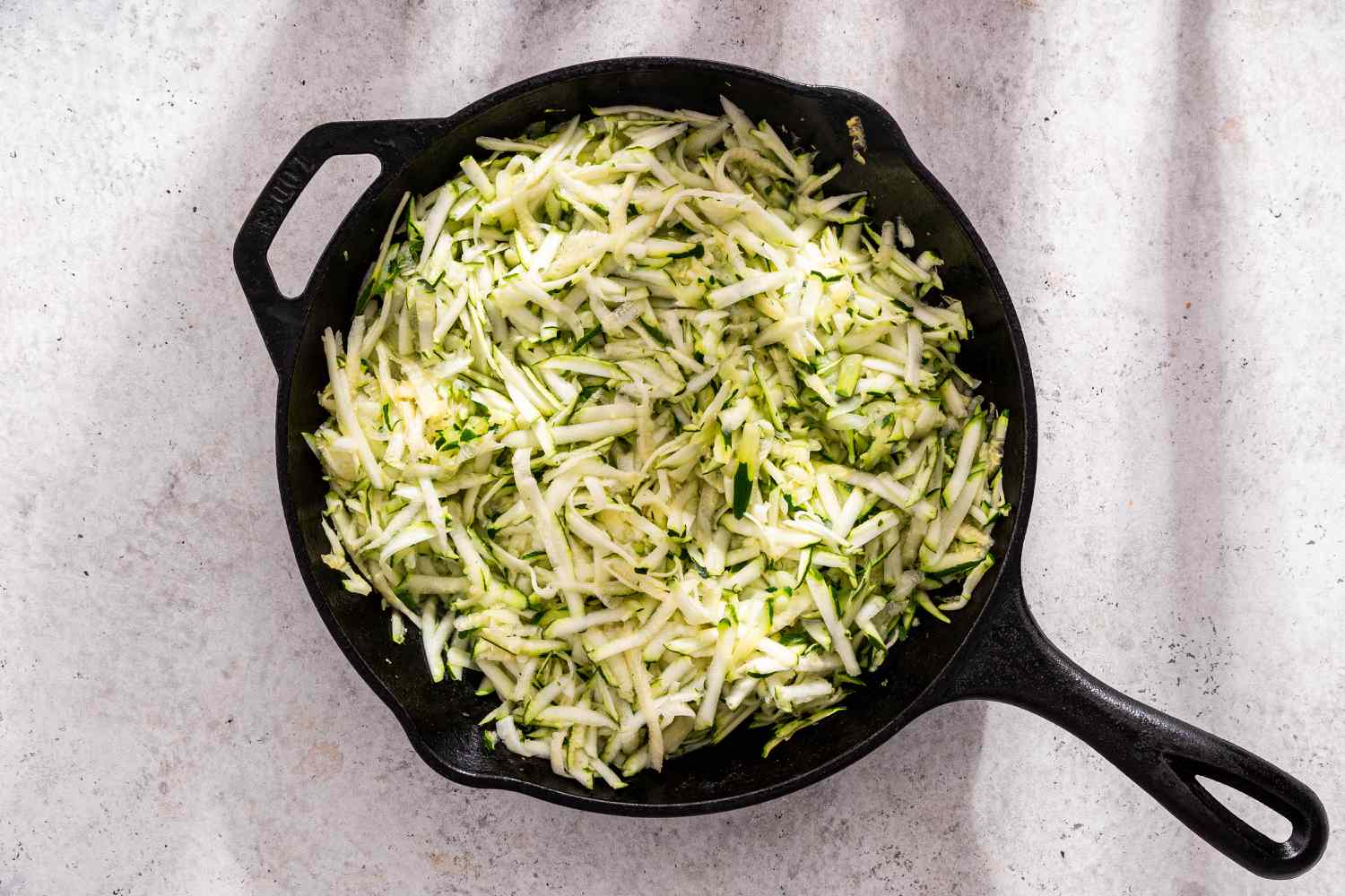 Grated Zucchini Added to Cast Iron Skillet for Zucchini Butter Recipe