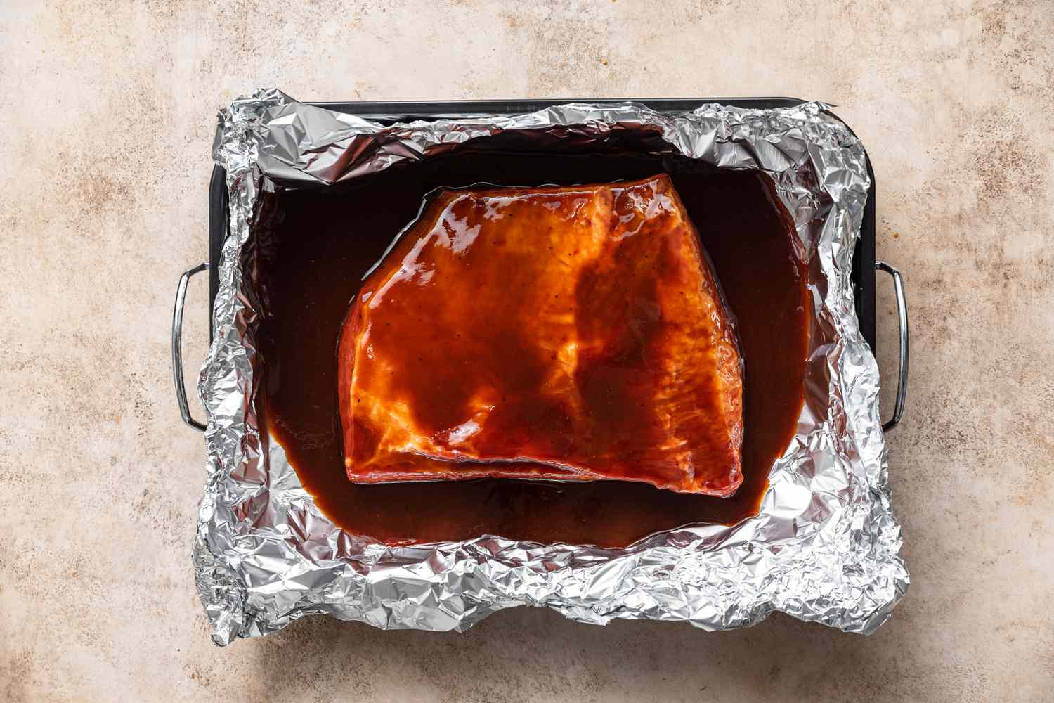 Beef Brisket in a foil-lined pan with sauce on top, ready to bake in the oven