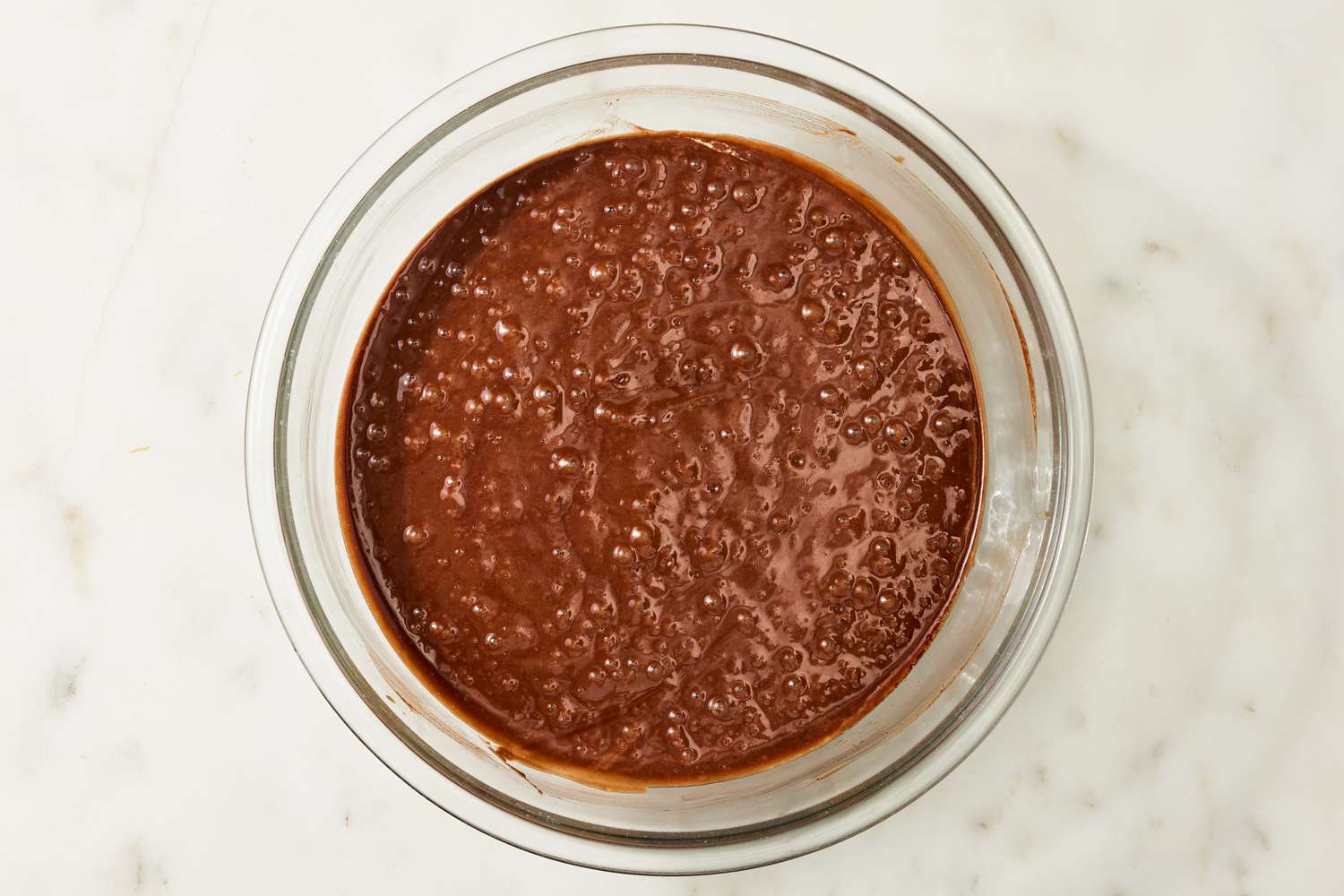 Overhead view of a clear glass bowl of batter for Coca Cola Cake recipe