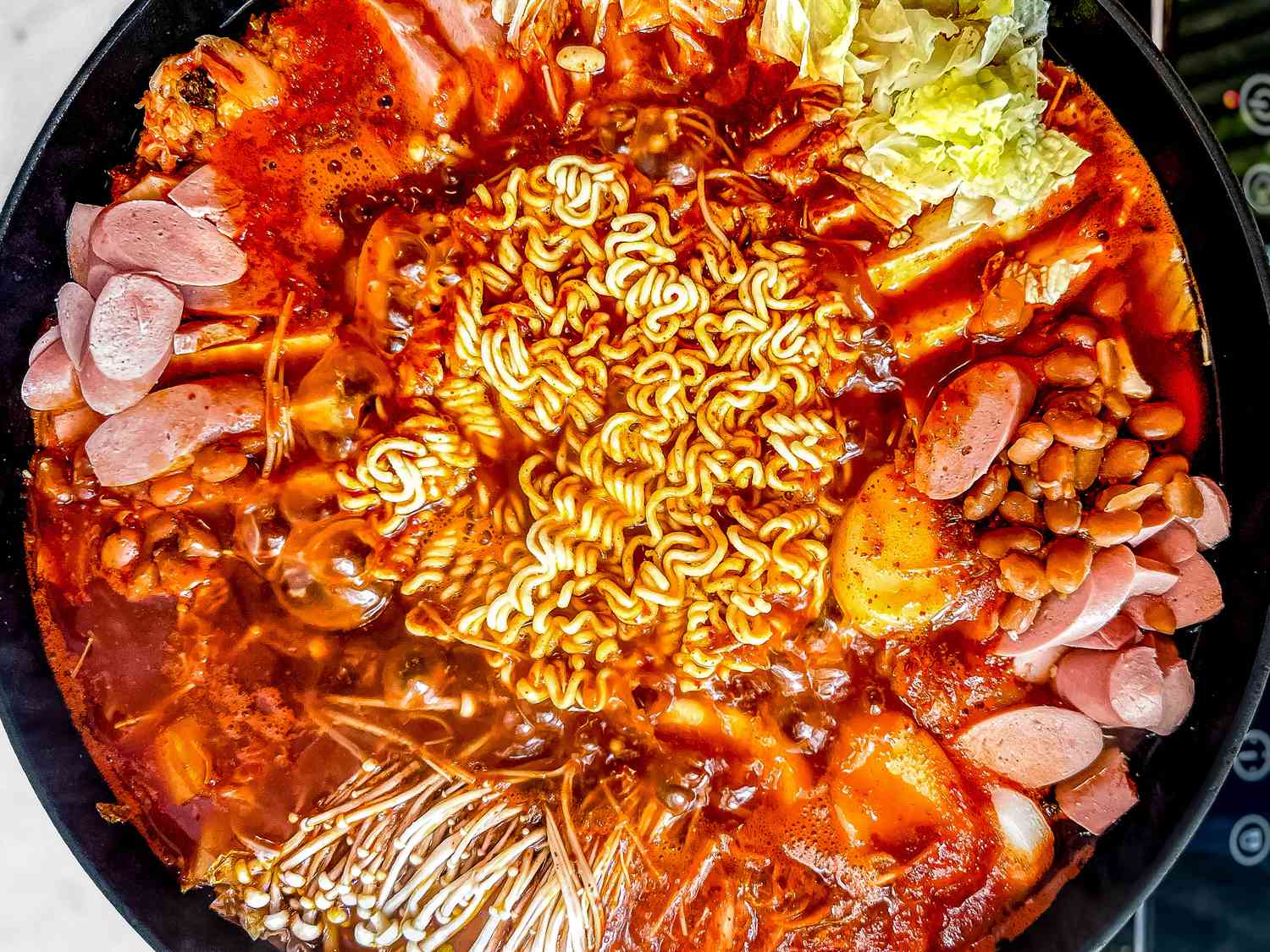 Budae Jjigae (Army Base Stew) in a large pot boiling on a portable induction stove