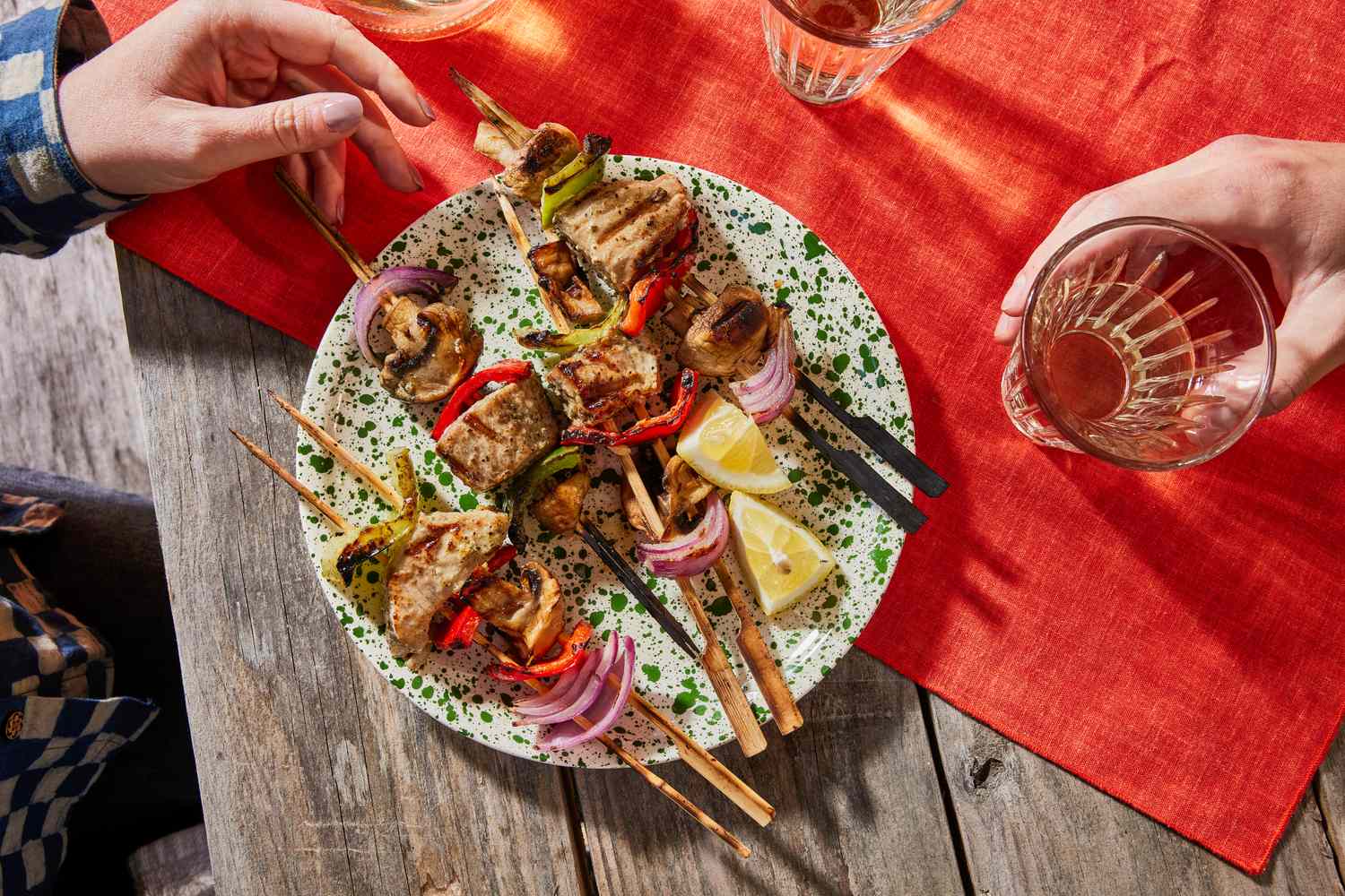 Plate of grilled tuna kebabs with vegetables on skewers, garnished with lemon