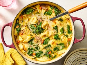 A pot of creamy tortellini soup with spinach and vegetables